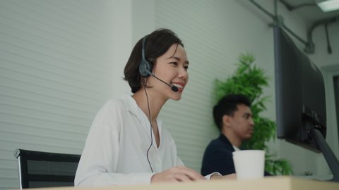 close up asian employee call center woman with colleagues response answer from customer or partner in operation room for business and technology concept.