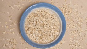 Rolled oats grains and plate mockup. Oats grains falling into plate. 4k video shot.