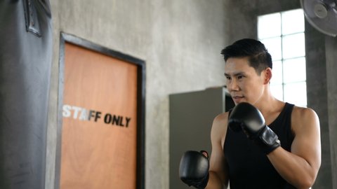 Fitness concept. A young Asian man is punching in the gym. 4k Resolution.