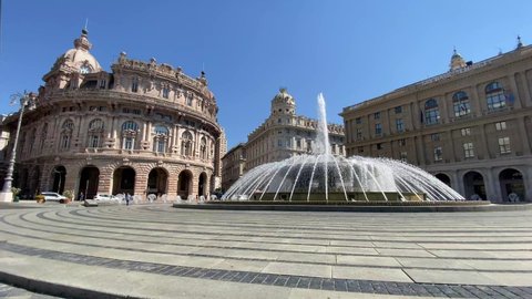 Genova, Italy, fountain in De Ferrari square, the heart of the city with the central fountain and the Liberty architecture of the Stock Exchange palace
