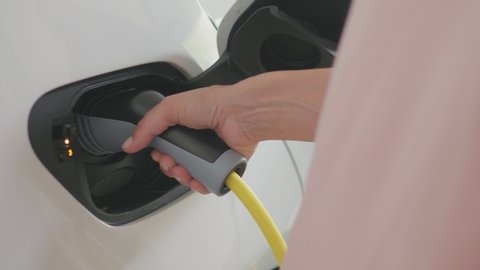 CU shot of a woman's hands plugging in her electric car to charge
