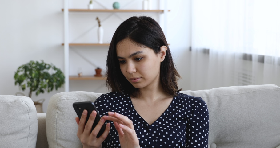 Asian woman sit on sofa hold cellphone read unpleasant news bad sms feels upset start crying. Bank notice about debt, student unsuccessful exam pass, not hired of dream job. Moment of failure concept | Shutterstock HD Video #1055094488