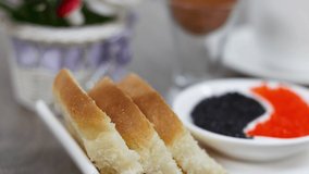 Morning breakfast with bread slices and red and black salty with boiled egg caviar on wooden table background.