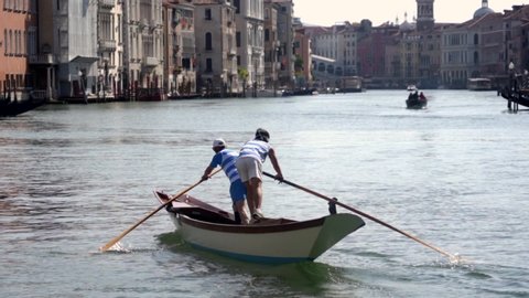 Venice, Italy - 2020 Gondoliers row in their gondola in the canal grande near the bridge of Rialto one of the most famous bridge in Venezia.