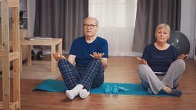 Senior couple doing yoga sitting on mat in living room. Old person healthy lifestyle exercise at home, workout and training, sport activity at home