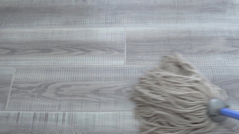 Cleaning a grey linoleum floor with white cotton mop. Close-up view on the cotton mop from above. House keeping