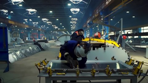 Factory Worker at Advanced Factory of railcar manufacturer train production plant, wide cinematic shot, dolly out