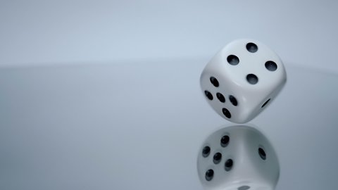 Cube dice slowly flips side to side on a mirror surface. Closeup. Shallow depth of field. Slow motion. High speed camera