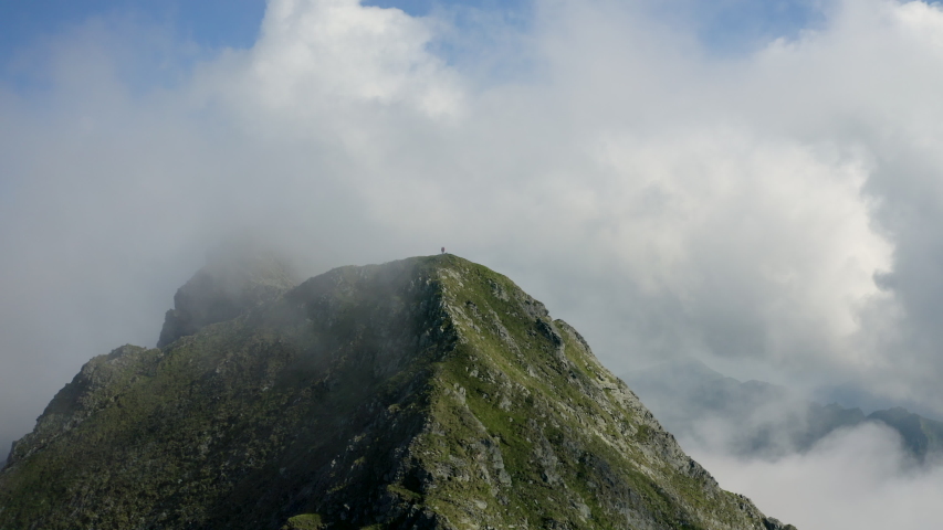 Two travelers on top of a mountain covered by clouds