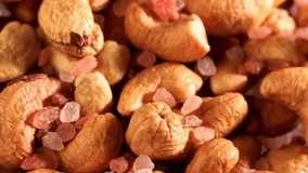 Video of cashews nut and Himalayan pink salt rotates slowly. Closeup shot in 4K resolution. Healthy food for dieting or snack.
