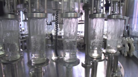 Factory for bottling alcohol. Working machine with conveyor line for production of alcoholic beverages. Glass bottles with vodka in conveyor belt in distillery production line.
