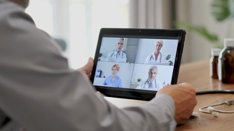 doctor in self isolation remote working from home,having a video call conference with colleagues online,medical workteam discussing on livestream chat using tablet