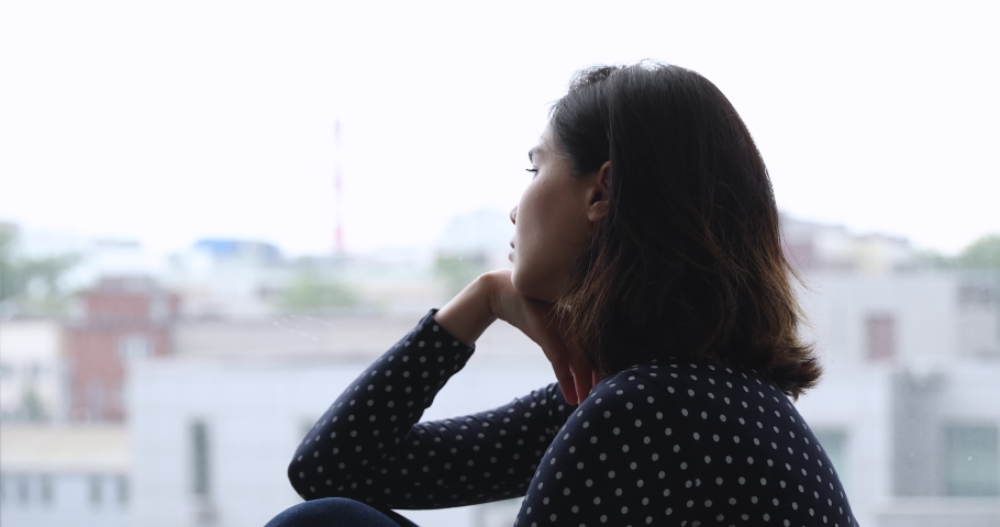 Close up side profile view sad asian young woman sitting on the windowsill feels depressed. Life troubles, break up broken heart and divorce, lonely single female, melancholy and rough weather concept | Shutterstock HD Video #1055106485