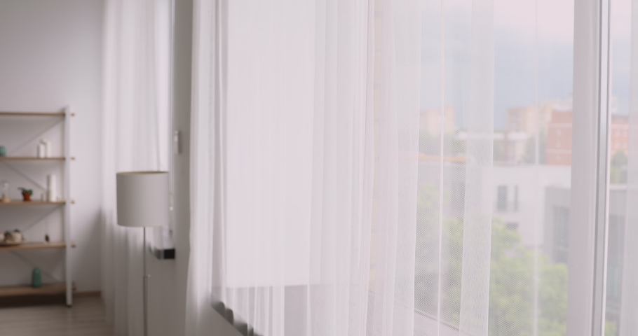 Vietnamese ethnicity young woman come to window in cozy modern living room opens curtains breathes fresh air-conditioned air admires view dreams of the future enjoys morning starting new day concept Royalty-Free Stock Footage #1055106488