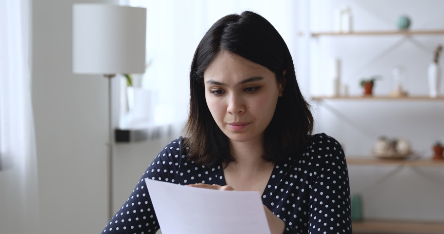 Asian woman sit at desk at home read letter about debt feels upset. Employee receive at workplace bad news holds dismissal staff cuts notice. Student university expulsion, scholarship revoked concept Royalty-Free Stock Footage #1055106521
