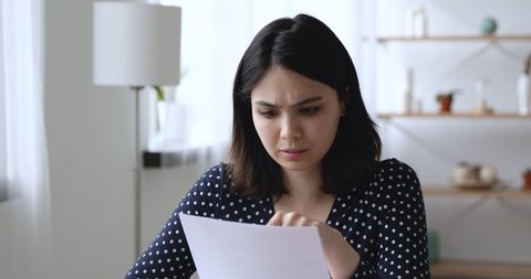 Asian woman sit at desk at home read letter about debt feels upset. Employee receive at workplace bad news holds dismissal staff cuts notice. Student university expulsion, scholarship revoked concept