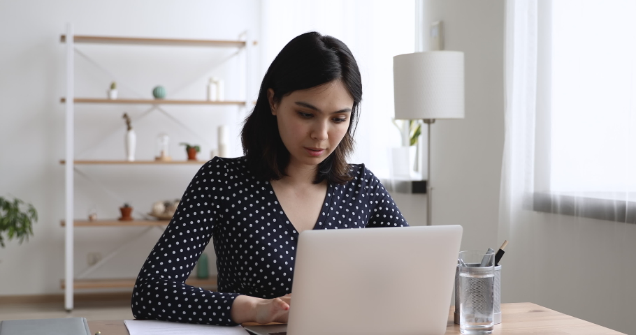 Happy asian young woman sit at desk at home or workplace typing on laptop receive great news celebrating moment of victory, personal achievement, got hired, high school scholarship admission concept Royalty-Free Stock Footage #1055106539