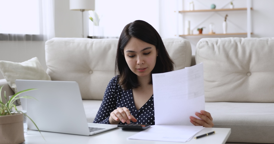 Vietnamese woman sit at coffee table in living room holding paper checking domestic bills calculates data feels upset due high prices or debt. Lack of finances, financial problems, bankruptcy concept Royalty-Free Stock Footage #1055106590