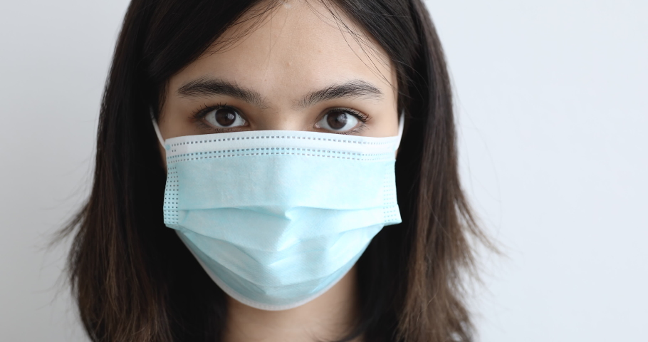 Close up Asian woman in blue medical face mask wears protective gloves bring nearer hands to camera makes heart shape looks through fingers. Take care of yourself at COVID-19 pandemic disease concept Royalty-Free Stock Footage #1055106740
