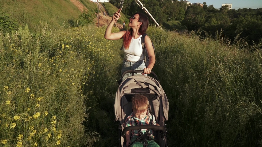 A boy with mom in a stroller near an old fortress in tall grass