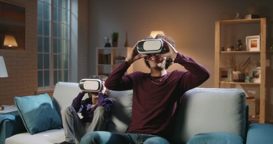 Authentic south asian siblings are having an experience in virtual reality, enjoying their together time at home in the evening - modern technologies, family time concept 4k footage