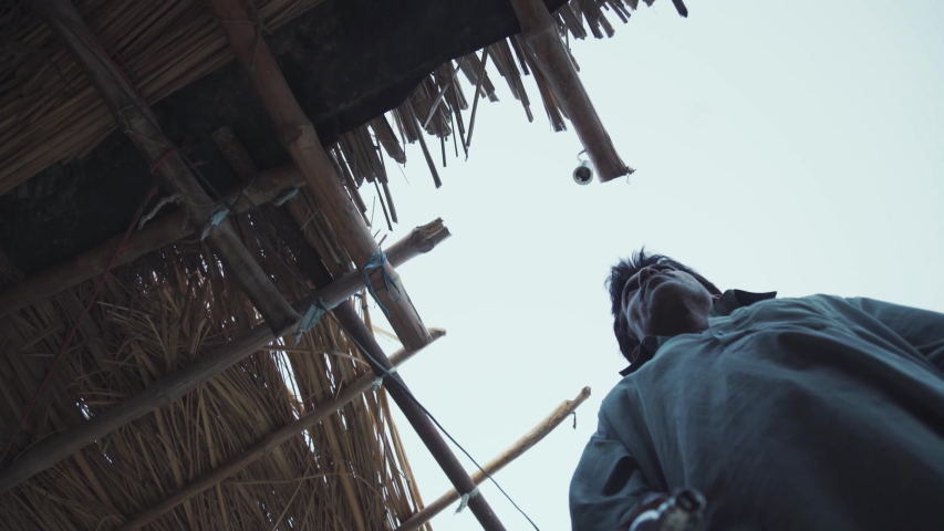 Man fixes light bulb on a straw hut