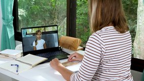 Female teacher has distance education lesson by Laptop with little school girl. Make video call to teach math and counting. Online class or e-learning at home