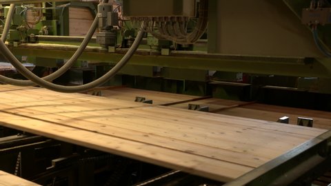 Viele einzelne Bretter werden maschinell zu einem Stapel zusammengeführt. Großes Sägewerk im Schwarzwald in dem indsutriell Bauholz wird wird.