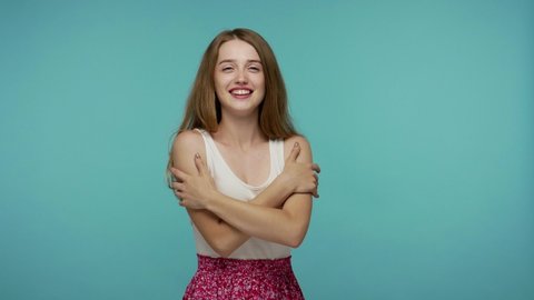 I love myself! Amazing cute girl with charming smile embracing herself, worshipping her own beauty, feeling selfish narcissistic, complacency concept. indoor studio shot isolated on blue background