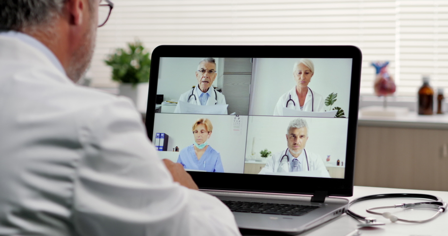 social distancing doctor makes a video call conference with his workteam online,group of doctors talking on livestream chat app greeting with an elbow bump Royalty-Free Stock Footage #1055129807