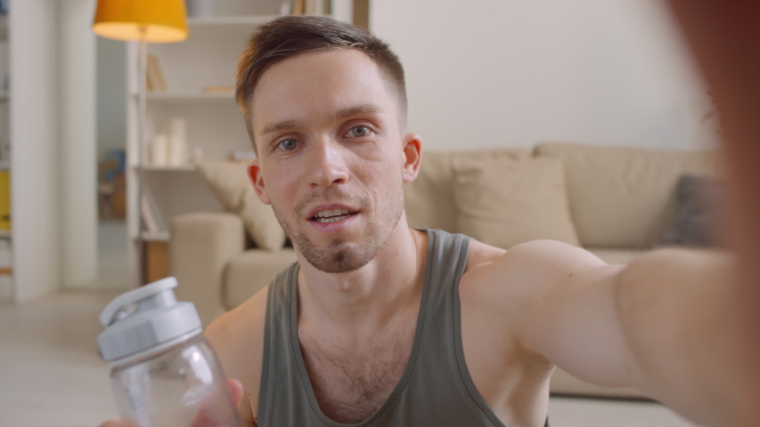 Modern personal trainer holding his smartphone giving online consultation to his followers during antiviral self-quarantine period