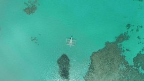 Aerial drone view of traditional philippine boat bangka anchored in the bay with clear and turquoise water on sunny day. Boat in the tropical lagoon. El Nido, Palawan island, Philippines.