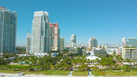 Aerial drone panorama view flight over Miami beach. South Beach sand and sea from above at sunny day. Miami Beach chairs and umbrellas on the coastline. Cinematic video of a luxury resort in Miami.