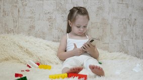 The child plays in the smartphone in the room. Distance learning of preschoolers online.