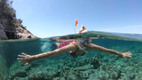 Woman snorkeler in Saint Andrew beach with reef and fishes of Elba island. Woman underwater snorkeling in Tyrrhenian sea on holiday travel, Italy. Saint andrew is Tuscan archipelago NP marine reserve.