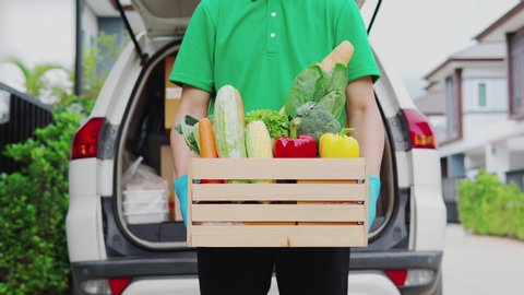 Portrait of Asian smart food delivery service man in green uniform handing fresh food holding  box of food looking at camera and smileOnline shopping delivering, smart food express delivery service co