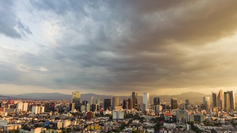 Hyperlapse top view flies over business, industrial and financial district of Mexico City, with skyscrapers of Paseo de la Reforma, on a dramatic cloudy day during the golden hour before sunset