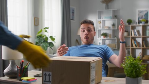 A young handsome man makes an online order and the delivery man immediately puts the parcel on his desk