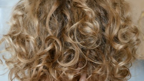 blond woman curly hair styling with  dryer closeup