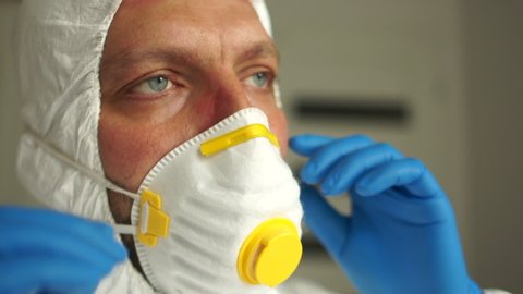Close portrait of a tired doctor. Male doctor during a coronavirus pandemic covid-19 takes off glasses and a protective mask, face marks are visible from the mask, red spots