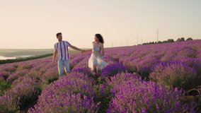 A happy couple in love runs on a lavender field, holding hands. Happiness, love, love. People smile at each other, a man and a woman look into each other's eyes. Sunset. - Powered by Shutterstock - Get 15% off with code: PIKWIZARD15