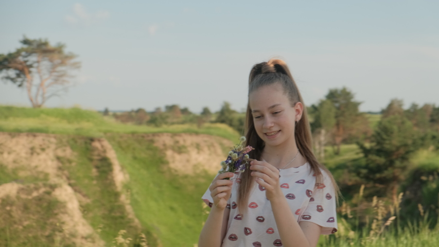 Close Up View Of Girl Smiling And Looking At Flowers In The Field. Positive Mood