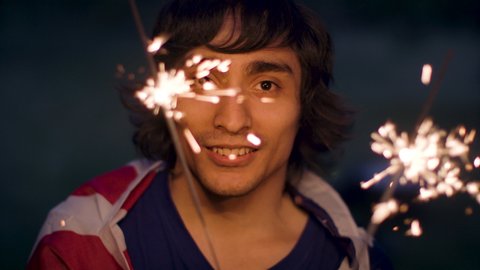 Celebrating Independence Day with sparklers. Man of Latin American descent enjoys 4th of July. Shot in slow-motion in 4k.