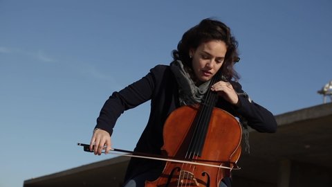 woman playing cello outdoors on a sunny day