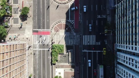 Top down aerial drone view over busy avenue in Copacabana with vehicles passing by and people crossing the street at the crosswalk. Rio de Janeiro