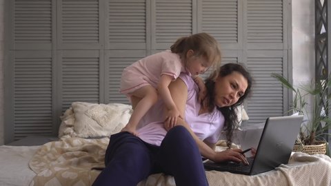 A multitasking mom working remote is stressed out. Problems associated with work at home. Noisy active child playing. Telecommute Job