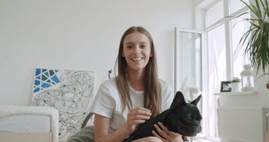 Smiling young woman blogger vlogger influencer sit at home with black french bulldog. Girl speaking looking at camera talking making video chat, conference call lifestyle blog vlog, webcam view