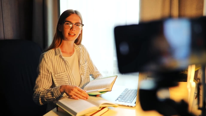  attractive, focused young woman in a medical protective face mask, conducting online training or shooting a Business course on a mobile phone on a tripod, sitting at a Desk at home Royalty-Free Stock Footage #1055185841