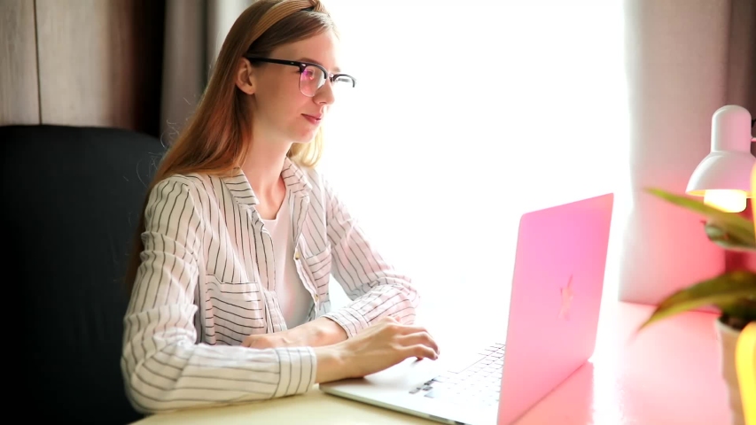 young smiling woman with glasses communicating with a client via a laptop video link, a female tutor giving online language lessons, distance learning, trainings Royalty-Free Stock Footage #1055185850