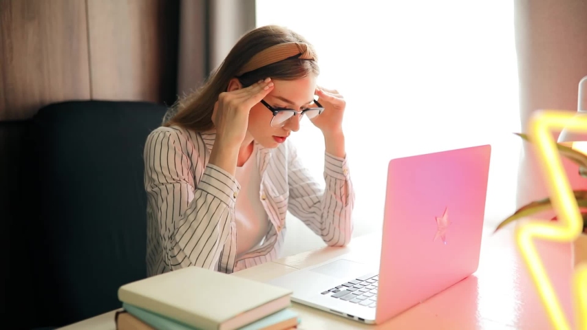  irritated girl is a student, studying at home, sitting at a table with textbooks and typing something on a laptop. Distance learning, quarantine, coronavirus Royalty-Free Stock Footage #1055185877